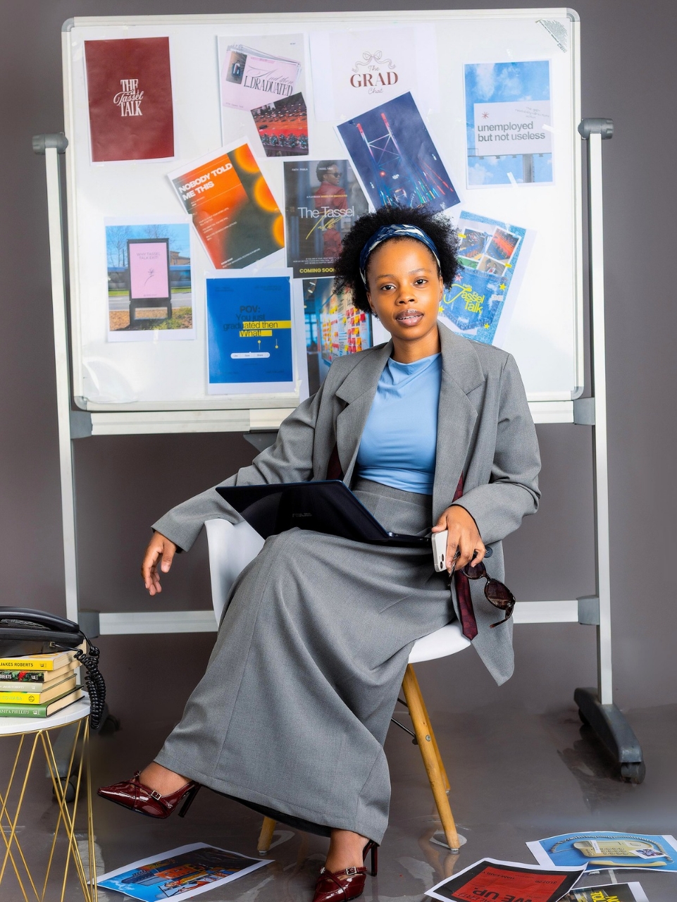 Tassel Talk founder seated with a laptop in front of a mood board of graduate posters